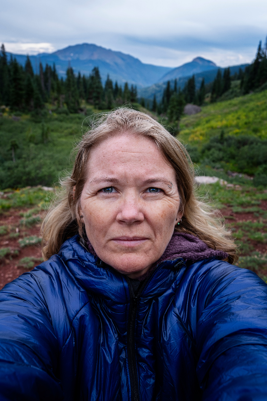 a woman stands in a mountain wilderness 